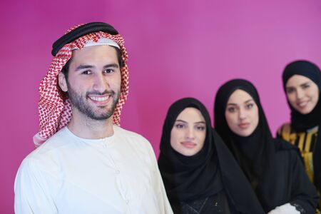 group portrait of young muslim people arabian man with three muslim women in fashionable dress with hijab isolated on pink background representing modern islam fashion and ramadan kareem conceptの写真素材