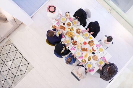 Eid Mubarak Muslim people praying before iftar dinner. Eating traditional food during Ramadan feasting month at home. The Islamic Halal Eating and Drinking at modern western Islamic family top viewの写真素材