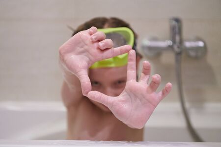 little girl with snorkel goggles in the tub while taking a bath in the bathtub, kids hygiene concept and summer vacation in corona virus stay at homeの写真素材