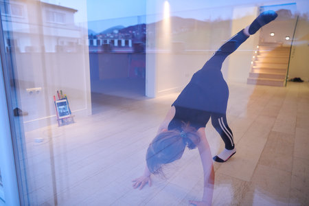 Little girl have online training while watching the tablet and doing fitness and modern ballet dance...