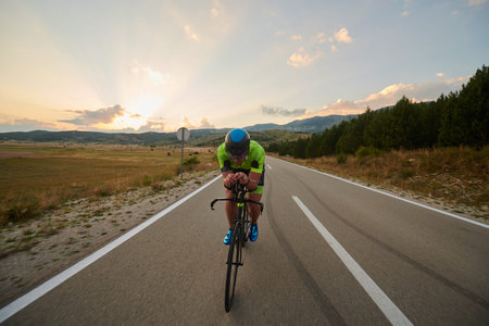 triathlon athlete riding professional racing bike at workout on curvy country road