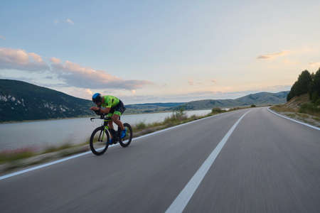 triathlon athlete riding professional racing bike at workout on curvy country roadの写真素材