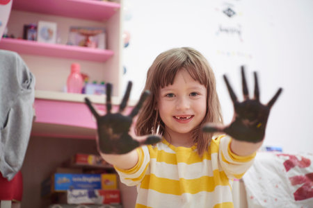 cute little girl at home painting with handsの写真素材