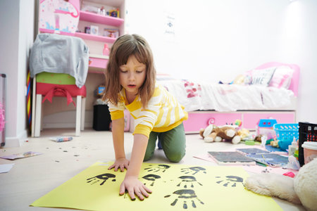 cute little girl at home painting with hands