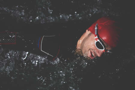 triathlon athlete swimming in dark night wearing wetsuitの写真素材