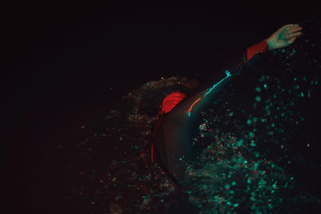 authentic triathlete swimmer having a break during hard training on night neon gel light