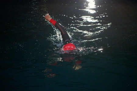 triathlon athlete swimming in dark night wearing wetsuit
