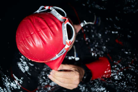 authentic triathlete swimmer having a break during hard training on nightの写真素材
