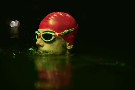 authentic triathlete swimmer having a break during hard training on night neon gel lightの写真素材