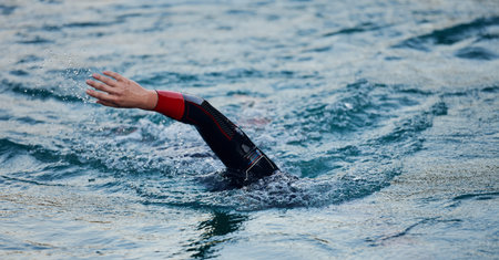 triathlon athlete swimming on lake in sunrise wearing wetsuit