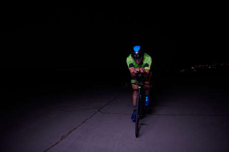 triathlon athlete riding bike fast at nightの写真素材
