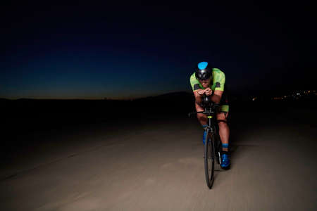 triathlon athlete riding bike fast at nightの写真素材