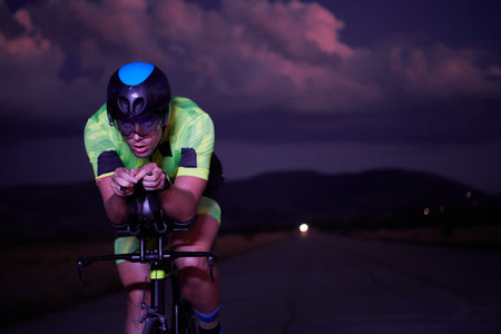 triathlon athlete riding bike fast at night
