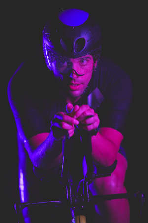 triathlon athlete riding bike fast at nightの写真素材