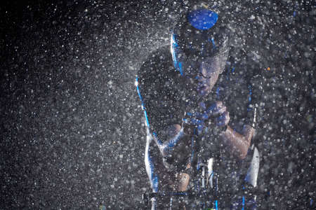 triathlon athlete riding bike fast on rainy nightの写真素材
