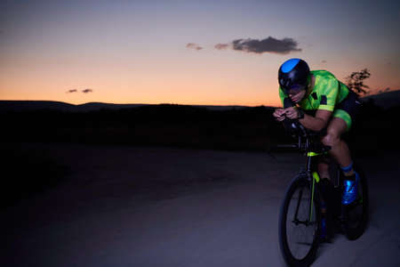 triathlon athlete riding bike fast at nightの写真素材