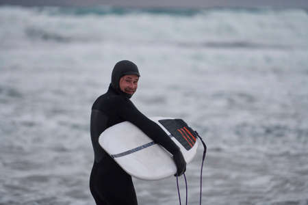 Arctic surfer going by beach after surfingの写真素材