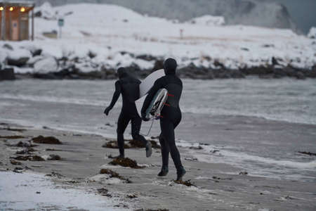 Arctic surfers running on beach after surfingの写真素材