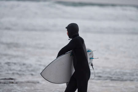 Arctic surfer going by beach after surfingの写真素材