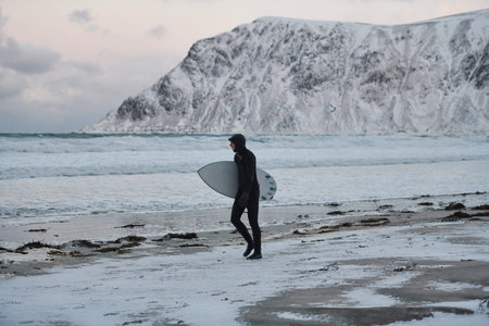 Arctic surfer going by beach after surfing