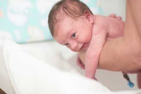 Newborn baby girl taking a first bath
