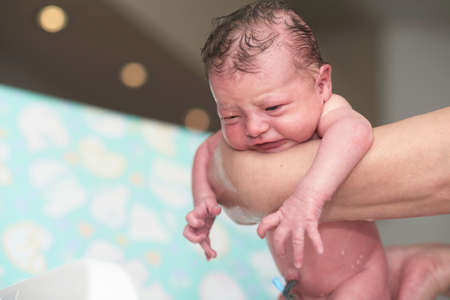 Newborn baby girl taking a first bathの写真素材