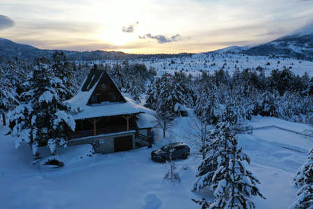 fresh snow covered trees and wooden cabin in wildernessの写真素材
