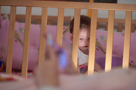 cute little one year old baby and making first steps in bedの写真素材