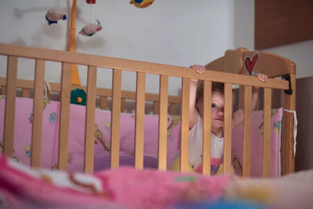 cute little one year old baby and making first steps in bedの写真素材