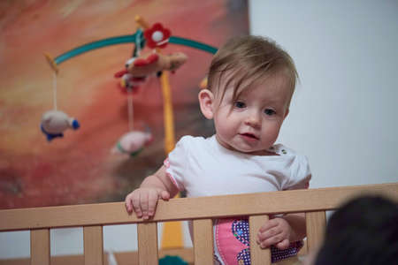 cute little one year old baby and making first steps in bedの写真素材