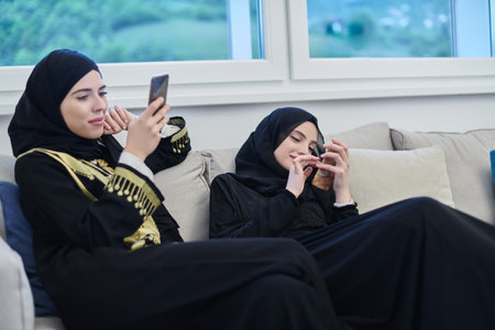 Portrait of Arabian girls wearing modern abaya using mobile phoneの写真素材