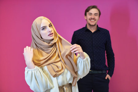 Portrait of happy young muslim couple standing isolated on pink background