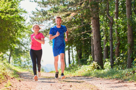 couple enjoying in a healthy lifestyle while jogging on a country roadの写真素材