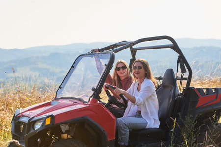 girls enjoying a beautiful sunny day while driving an off-road carの写真素材