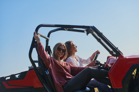girls enjoying a beautiful sunny day while driving an off-road carの写真素材