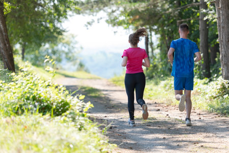 couple enjoying in a healthy lifestyle while jogging on a country roadの写真素材