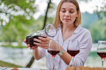 woman pouring red wine into glasses