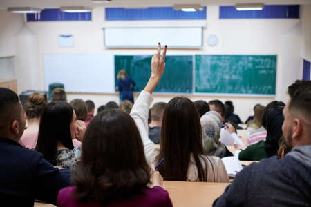 female student sitting in the class and raising hand upの写真素材