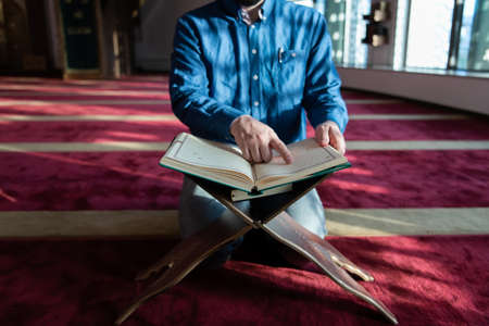 muslim man praying Allah alone inside the mosque and reading islamic holly bookの写真素材