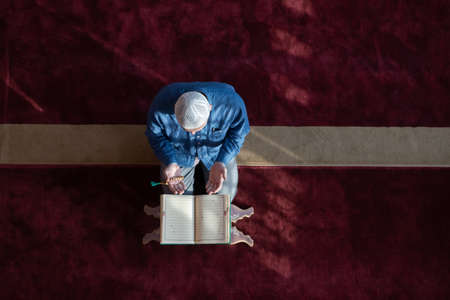 muslim man praying Allah alone inside the mosque and reading islamic holly bookの写真素材