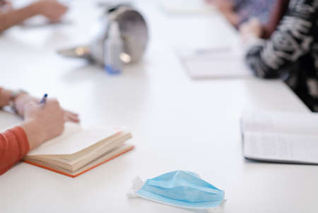 Closeup of protective medical face mask at desk on business meetingの写真素材