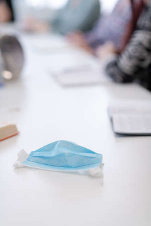 Closeup of protective medical face mask at desk on business meetingの写真素材