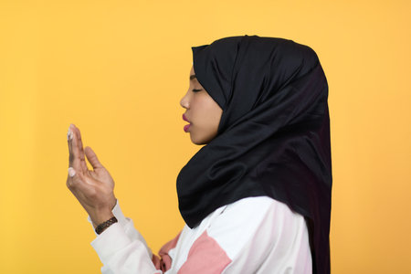 african muslim woman wearing hijab and traditional muslim clothes posing in front of green...