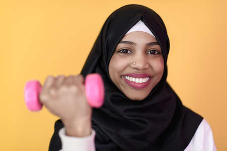 afro muslim woman promotes a healthy life, holding dumbbells in her handsの写真素材