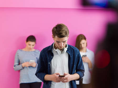 group of diverse teenagers use mobile devices while posing for studio photoの写真素材