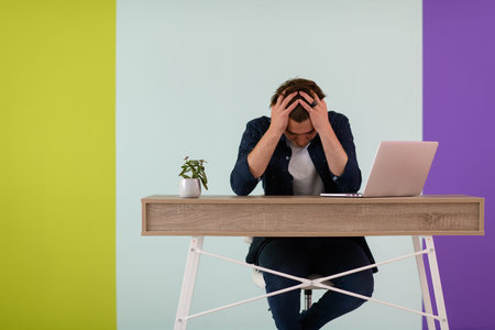 disappointed and annoyed man sitting at a table and looking at a laptop