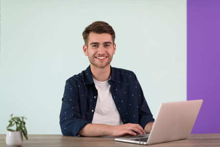 Smiling young man freelancer using laptop studying online working from home