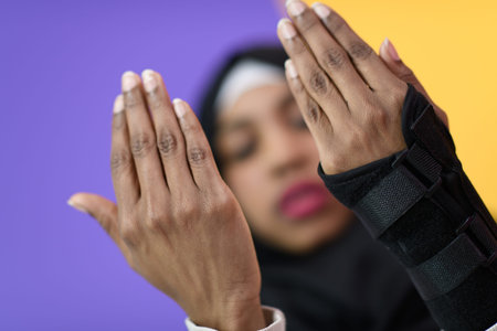 african muslim woman wearing hijab and traditional muslim clothes posing in front of green...