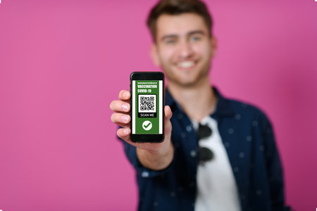 covid passport a young man shows his qr code and covid19 passport on his cell phoneの写真素材