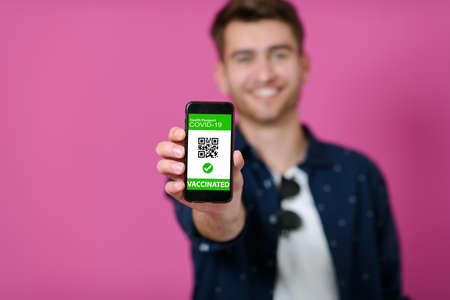 covid passport a young man shows his qr code and covid19 passport on his cell phoneの写真素材